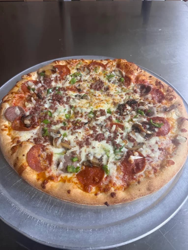 A pizza topped with pepperoni, vegetables, and melted cheese on a serving tray at Elizabeth’s Pizza