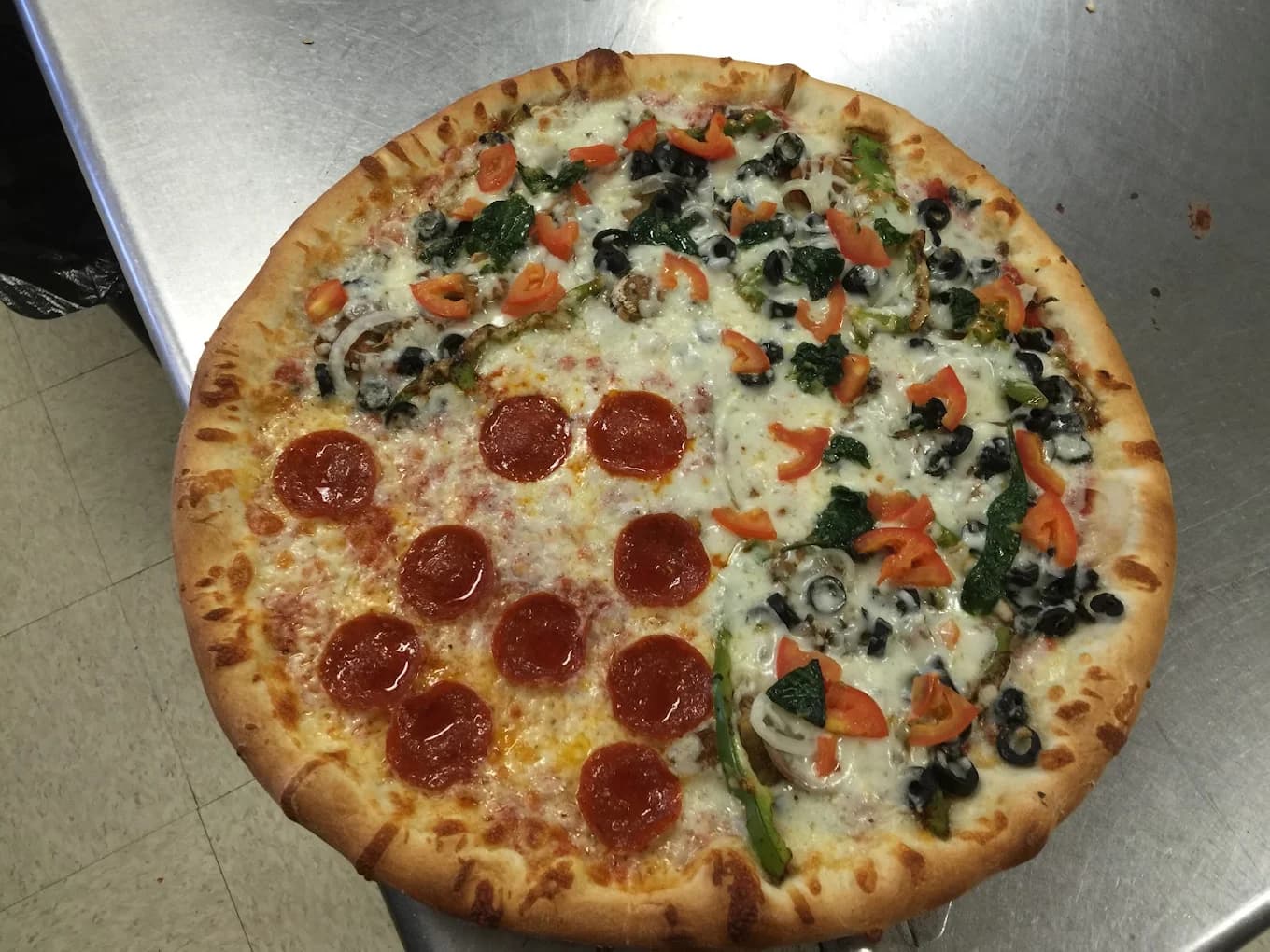 A pizza with sections of pepperoni and colorful vegetable toppings, ready to share