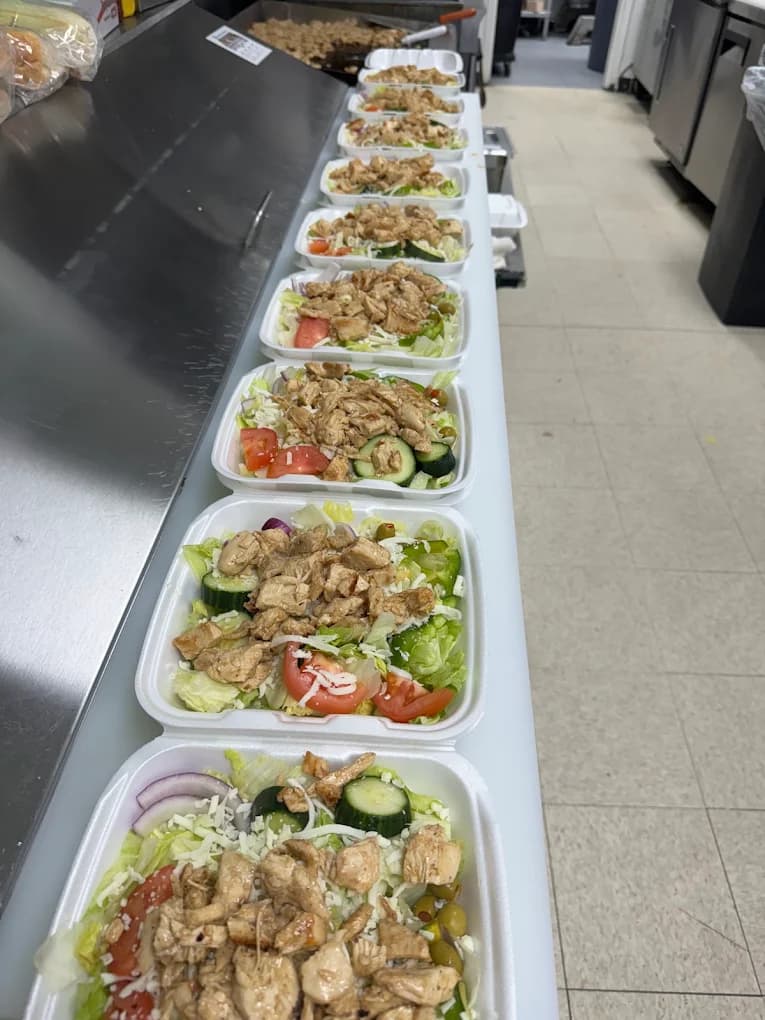 A row of grilled chicken salads packed in takeaway containers