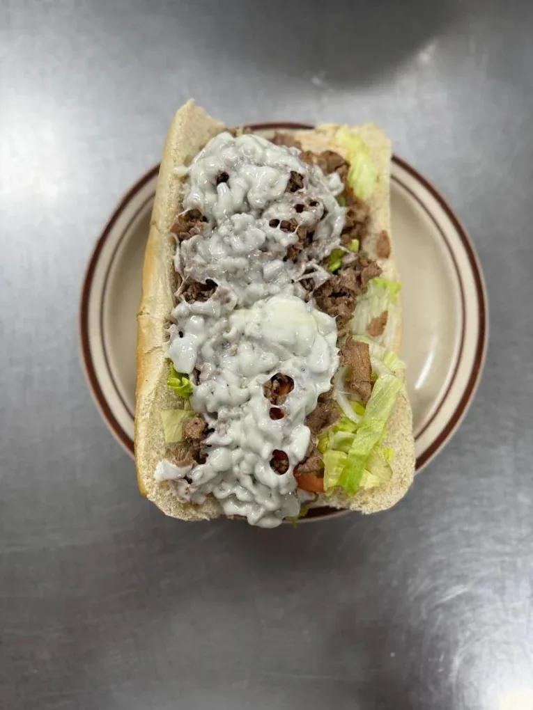 A cheesesteak with melted cheese and lettuce on a plate at Elizabeth’s Pizza